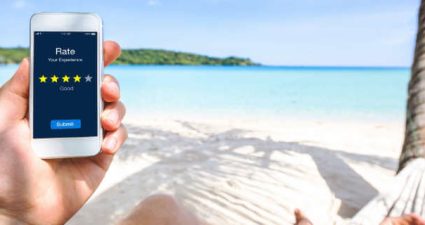 Mann mit Handy am Strand unter Palmen