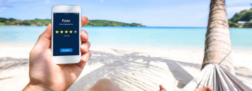 Mann mit Handy am Strand unter Palmen