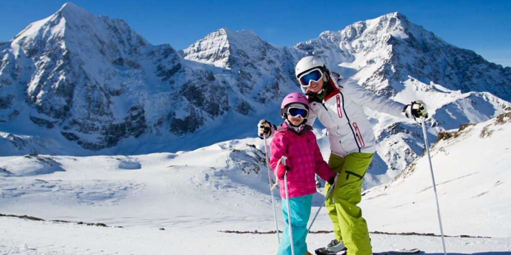 Frau mit Kind beim Ski fahren in den Alpen