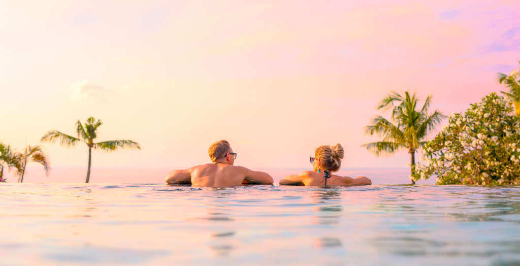 Romantisches Paar badet zum Sonnenuntergang im Infinity-Pool