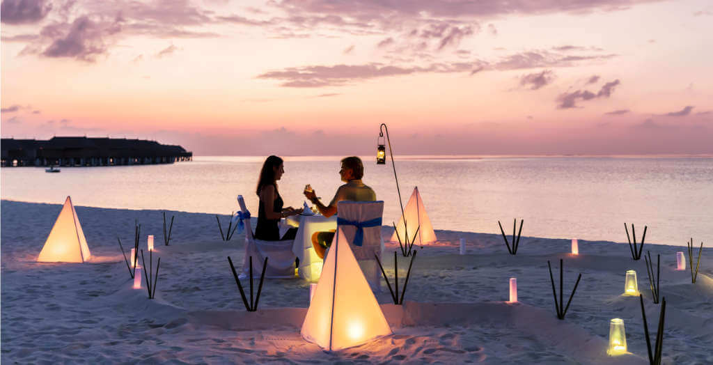 Paar genießt ihr Abendessen am tropsichen Strand