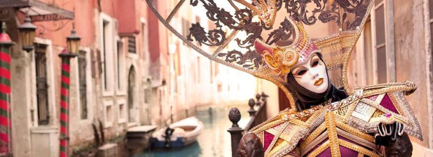 Kostümierte Frau mit Maske auf einem Kanal zum Karneval in Venedig, Italien