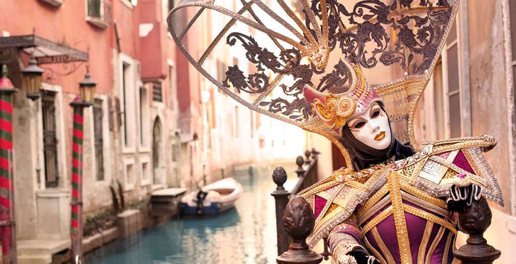 Kostümierte Frau mit Maske auf einem Kanal zum Karneval in Venedig, Italien