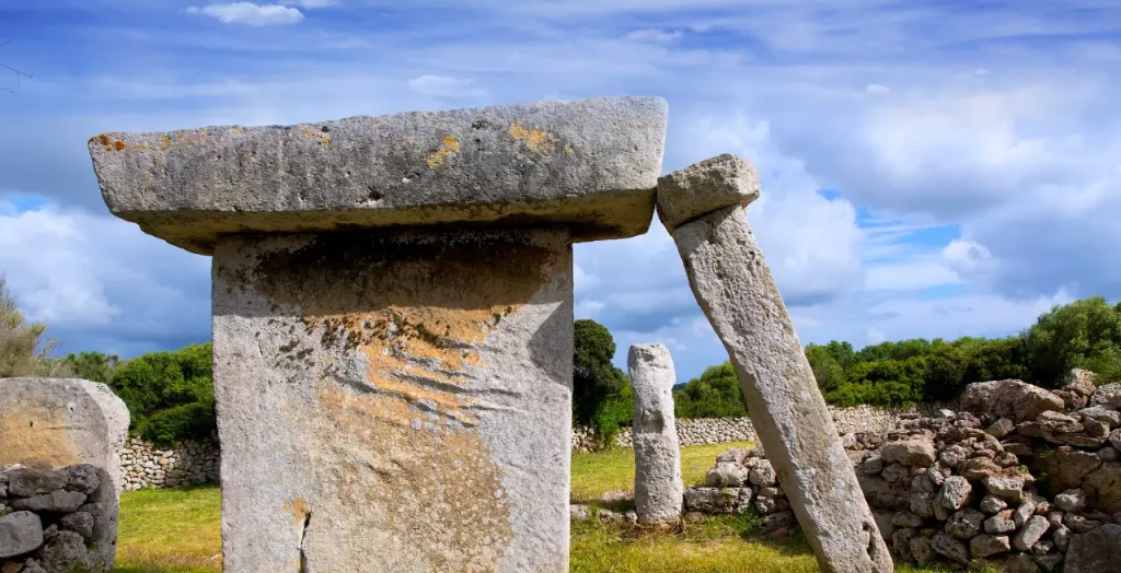 Prähistorische Taula von Talatí de Dalt auf Menorca, umgeben von üppigem Grün und traditionellen Steinmauern [Bildquelle: © Lunamarina | Canva]