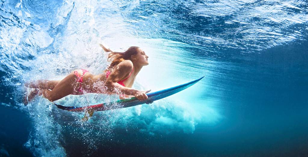 Frau surft mit Surfbrett Unterwasser