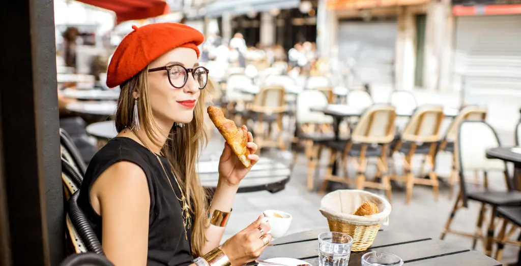 Frau genießt ihr französisches Frühstück in einem Café in Paris, Frankreich