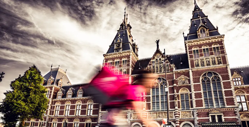 Fahrradfahrer in Bewegung vor der historischen Fassade des Rijksmuseum in Amsterdam, Niederlande
