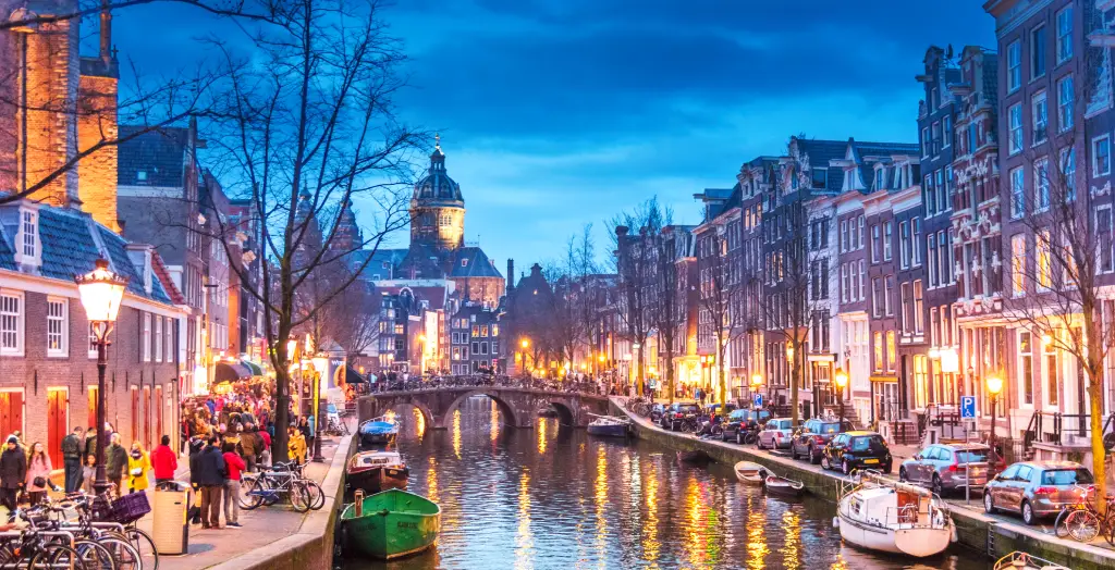 Belebte Abendstimmung an der Keizersgracht in Amsterdam, Niederlande, mit historischen Häusern und warm beleuchteten Straßenlaternen