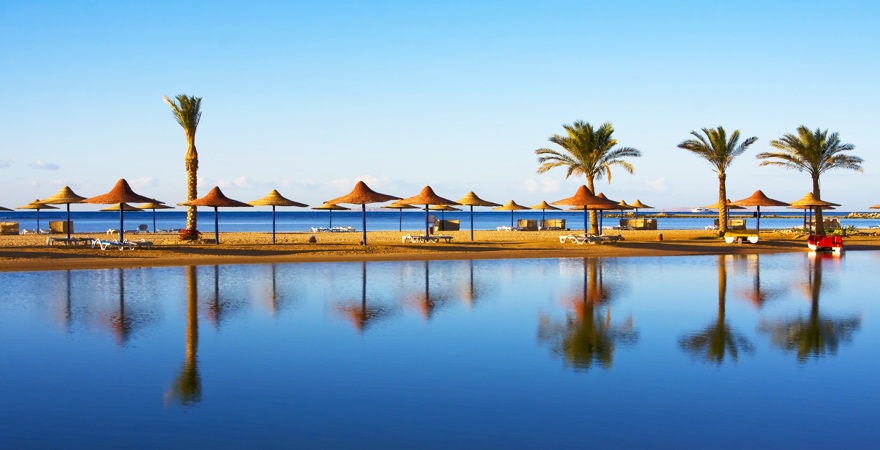 Strand von Hurghada mit Spieglung der Palmen und Schirme im Wasser