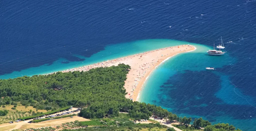 Drohnenaufnahme des Strandes Zlatni Rat, bekannt als das Goldene Horn, in Kroatien, charakteristisch durch seine einzigartige spitze Form und türkisfarbenes Wasser