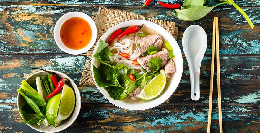 Vietnamesische Suppe Pho bo mit Kräutern, Fleisch, Reisnudeln und Brühe