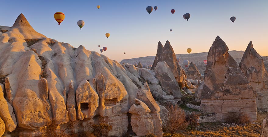 Über den Felsen Kappadokien fliegen viele Heißluftballons im Sonnenuntergang