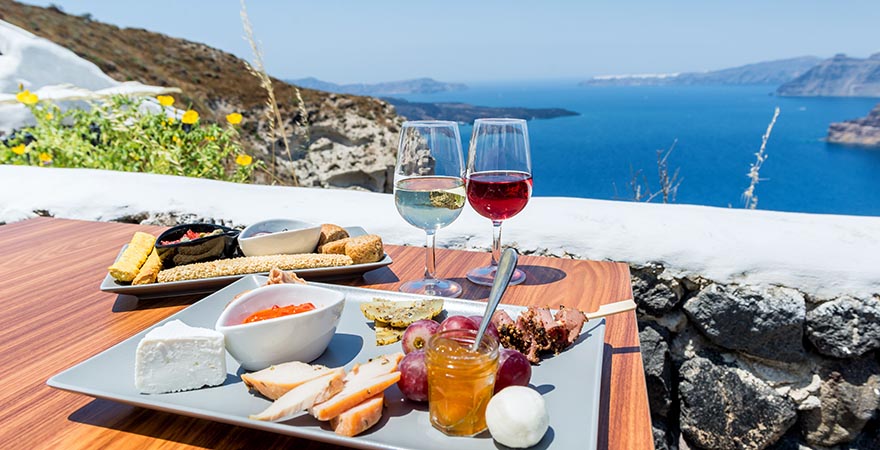 Weingläser und Essen mit Aussicht auf das Meer in Santorini