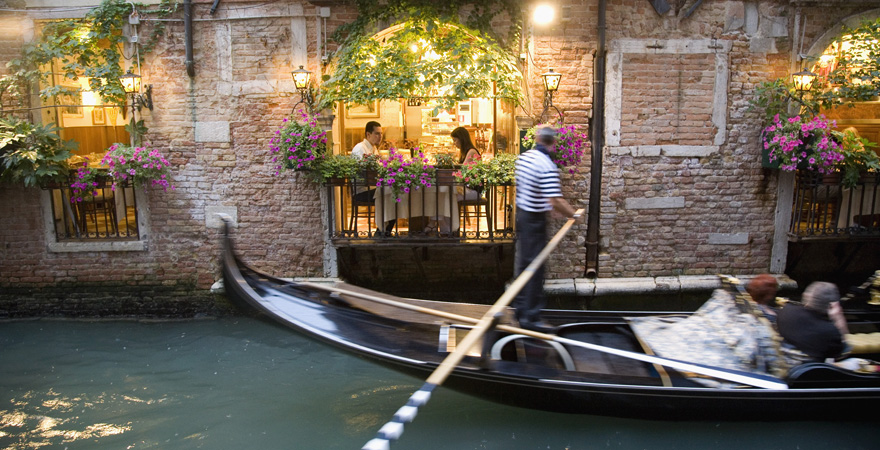 Paar beim Abendessen mit Ausblick auf die Gondelfahrten in Venedigs Kanälen