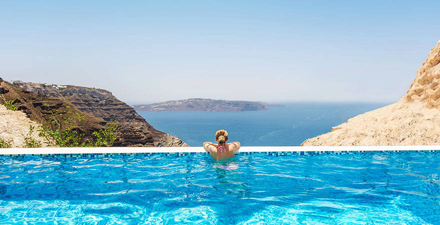Frau genießt Ausblick vom Infinitypool auf Santorini