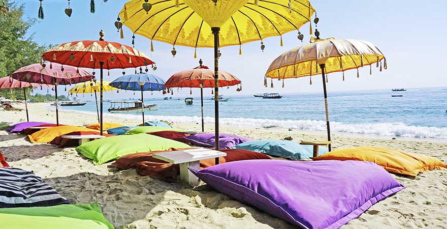 Bunte Sitzkissen und Sonnenschirme am Strand von Bali