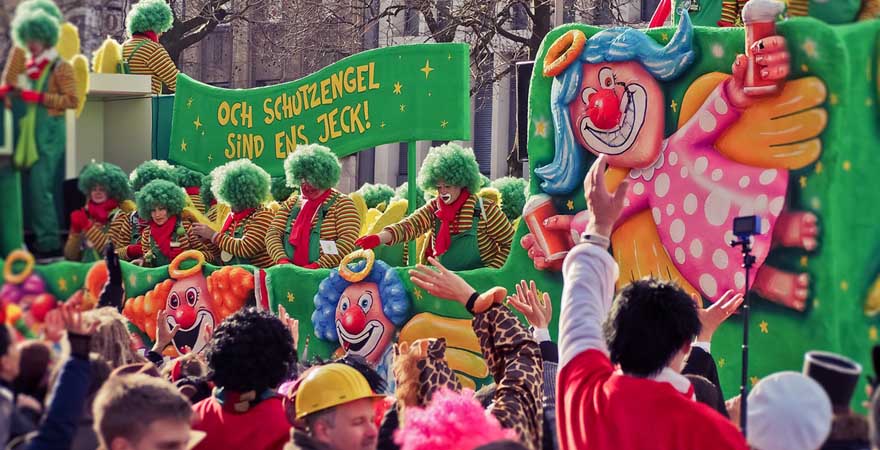 Bunter Festwagen mit kostümierten Personen zieht durch Düsseldorf