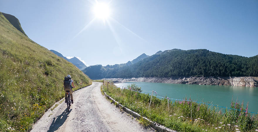 Ein Fahrradfahrer radelt entlang eines See´s in den Schweizer Alpen