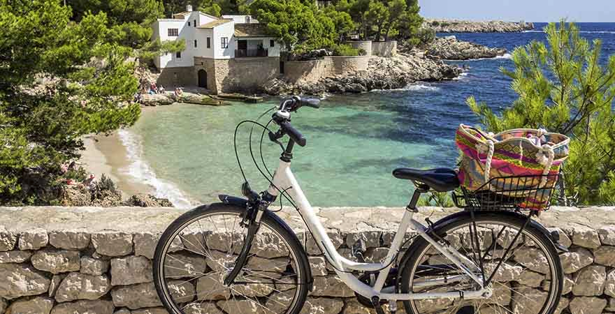 Fahrrad mit einer Tasche im Korb steht vor einer Finca am Mittelmeer vor Mallorca