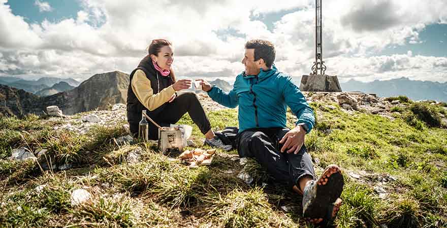Ein Paar sitzt auf dem Gipfel eines Berges und trinkt Tee