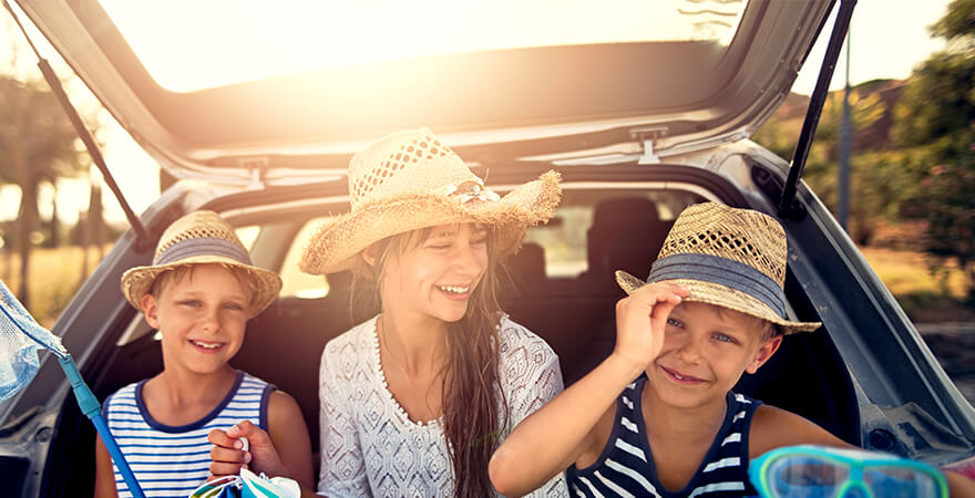 Kinder sitzen lachend im Kofferraum eines Autos