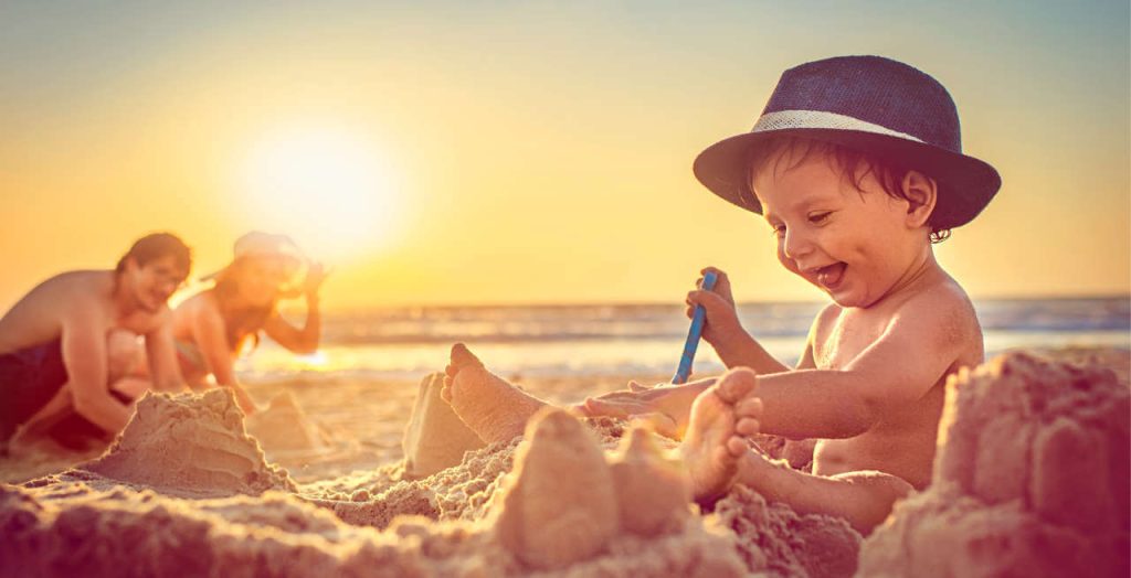 Ein kleines Kind genießt das Buddeln im Sand mit seiner Familie