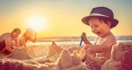 Ein kleines Kind genießt das Buddeln im Sand mit seiner Familie