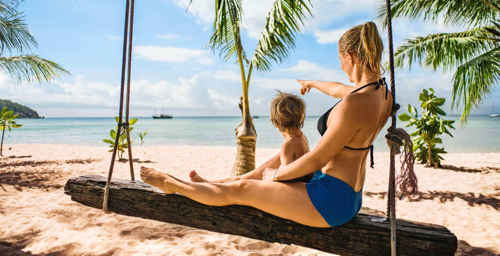 Mutter und Kind schaukeln am karibischen Strand