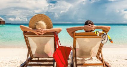 Paar entspannt am türkisfarbenen Meer auf Sonnenstühlen