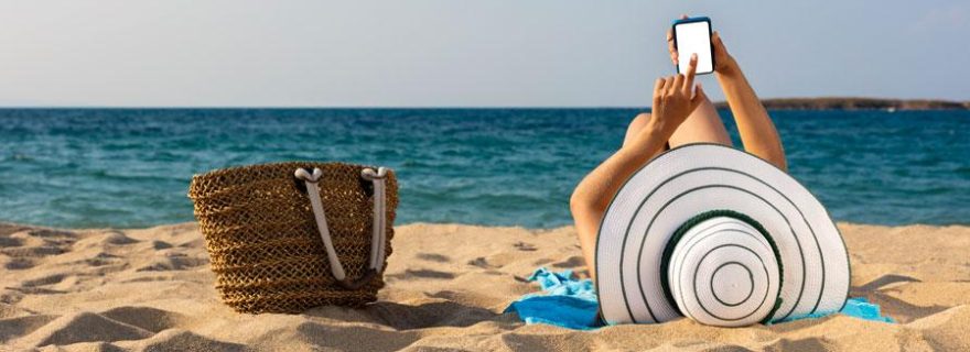 Frau entspannt mit ihrem Handy am Strand in der Türkei