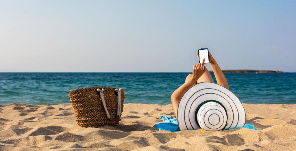 Frau entspannt mit ihrem Handy am Strand in der Türkei