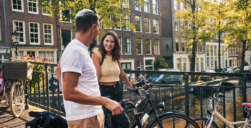 Junges Paar erkundet Amsterdam mit einem Fahrrad