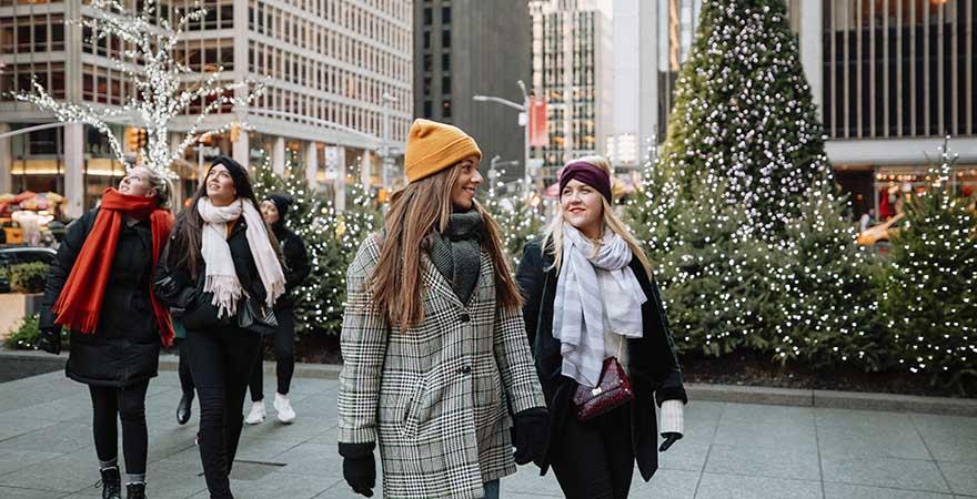Eine Gruppe von Frauen spaziert Seite an Seite und besichtigt New York zur Weihnachtszeit, USA