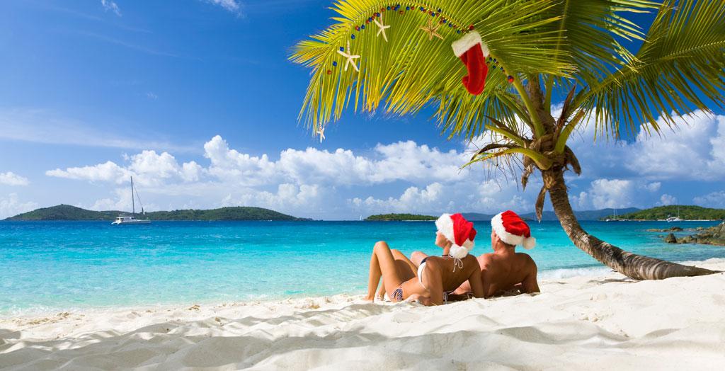 Paar genießt tropische Weihnachten unter einer geschmückten Palme an einem karibischen Strand