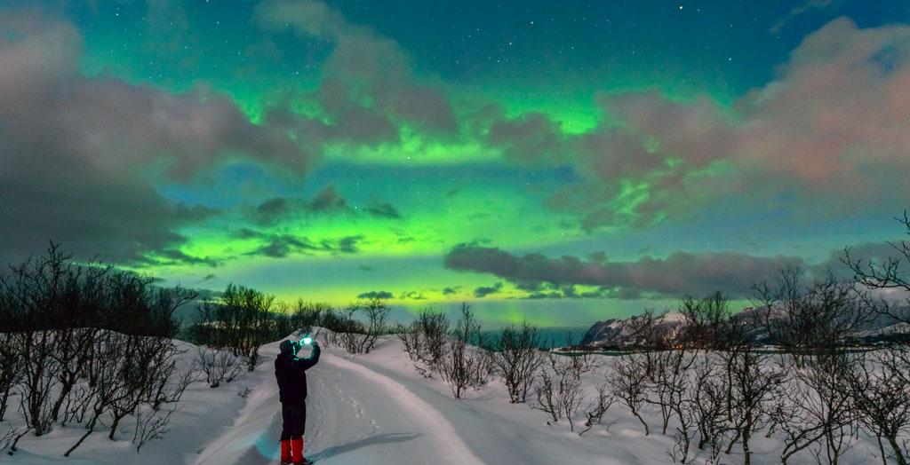 Mann fotografiert den Nachthimmel mit Polarlichtern über der Insel Senja in Norwegen