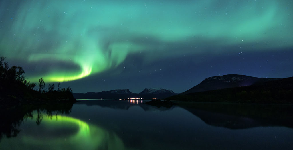 Polarlichter, Nordlichter spiegeln sich im Wasser in Abisko, Schweden