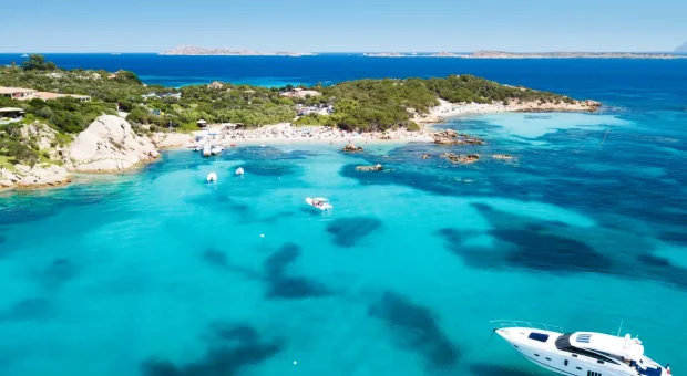 Atemberaubende Luftaufnahme der Bucht Cala Mariolu mit klarem türkisfarbenem Wasser und verankerten Booten, Sardinien, Italien