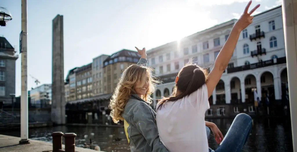 Zwei junge Mädchen umarmen sich liebevoll am Flussufer in Hamburg, Deutschland