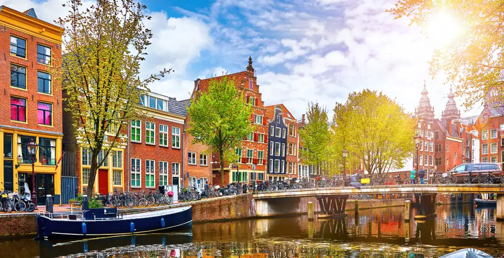 Herbstliche Sonnenstrahlen über den Grachten in Amsterdam, Niederlande, mit bunten Fassaden und einem ruhigen Kanal