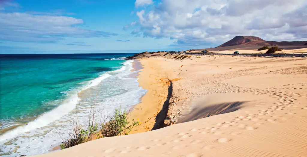 Die Dünen von Corralejo mit Blick auf das kristallklare Wasser und den Berg in der Ferne auf Fuerteventura, Kanarische Inseln.