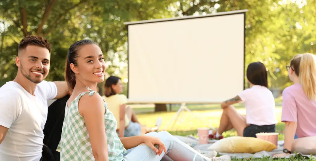 Junge Leute genießen ein Open-Air-Kino im Park an einem sonnigen Tag