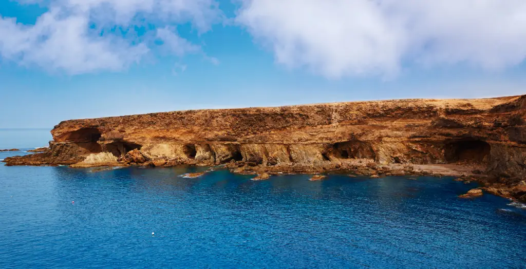 Die Höhlen von Ajuy an der Küste Fuerteventuras, unter einem blauen Himmel und über dem azurblauen Wasser der Kanarischen Inseln, Spanien. [Bildquelle: © Lunamarina | Canva]
