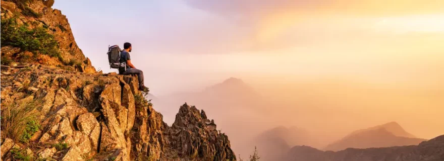 Wanderer sitzt in den Bergen in Al Baha und genießt den Sonnenuntergang, Saudi-Arabien