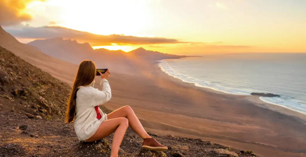 Junge Wanderin fotografiert den Sonnenuntergang im Naturpark Jandía, Fuerteventura, Kanaren