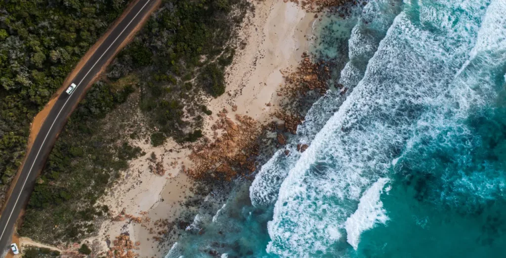 Drohnenblick auf Eagle Bay in Dunsborough, Westaustralien, mit wilder Küstenlinie, türkisfarbenem Wasser und Straße entlang des Strandes [Bildquelle: © Tourism Western Australia]