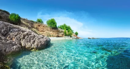 Kristallklares Wasser in einer ruhigen Bucht auf Hvar, Kroatien, mit felsiger Küste und grüner Vegetation