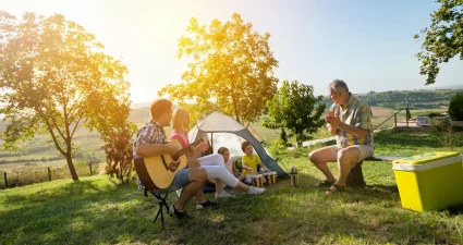 Familie genießt gemeinsames Picknick mit Musik und Spiel im Grünen [Bildquelle: © LuckyBusiness | Canva]