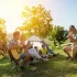 Familie genießt gemeinsames Picknick mit Musik und Spiel im Grünen [Bildquelle: © LuckyBusiness | Canva]