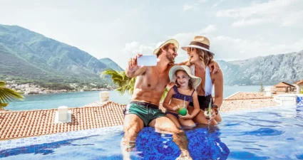 Familie genießt gemeinsame Zeit im Infinity-Pool mit malerischem Blick auf die Berge von Montenegro im Hintergrund