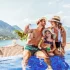 Familie genießt gemeinsame Zeit im Infinity-Pool mit malerischem Blick auf die Berge von Montenegro im Hintergrund